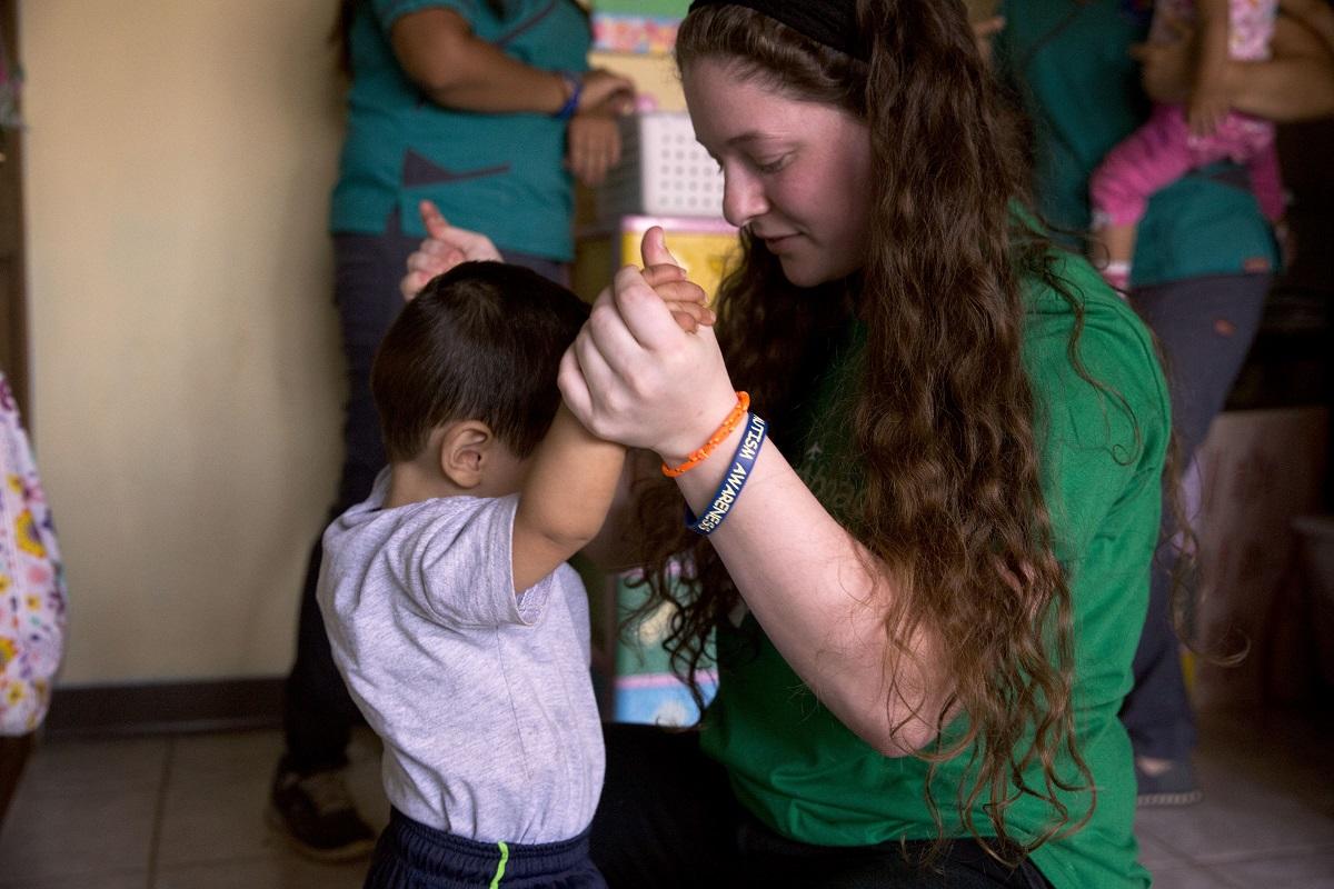 A volunteer helps a child to walk during her Childcare volunteer work in Costa Rica A Projects Abroad volunteer with children in Costa Rica, helps a young boy with his balance